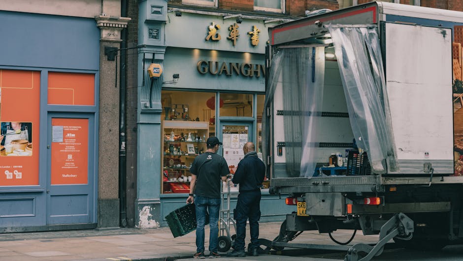 Two men are standing outside a shop with a sign that reads 'GUANGH' in Chinese characters above the entrance, which likely indicates a small retail or food establishment in Shepherds Bush. One man in